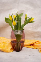 Violet Marika Vase Tall with yellow flowers, a patterned orange fabric and a white background