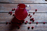 Underlay Garnet Hobnail Jug on a wooden table surrounded by small red Christmas baubles 