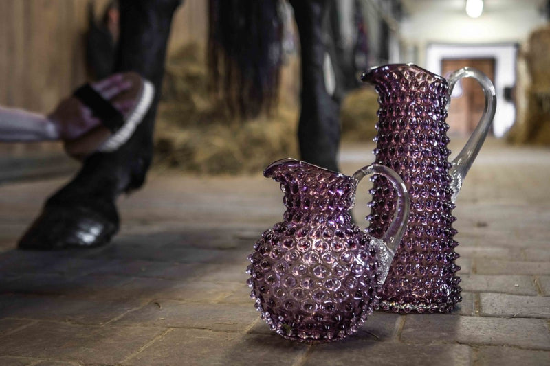 Underlay Violet Hobnail Jug Tall on a white stone floor with a stable and horse in the background 